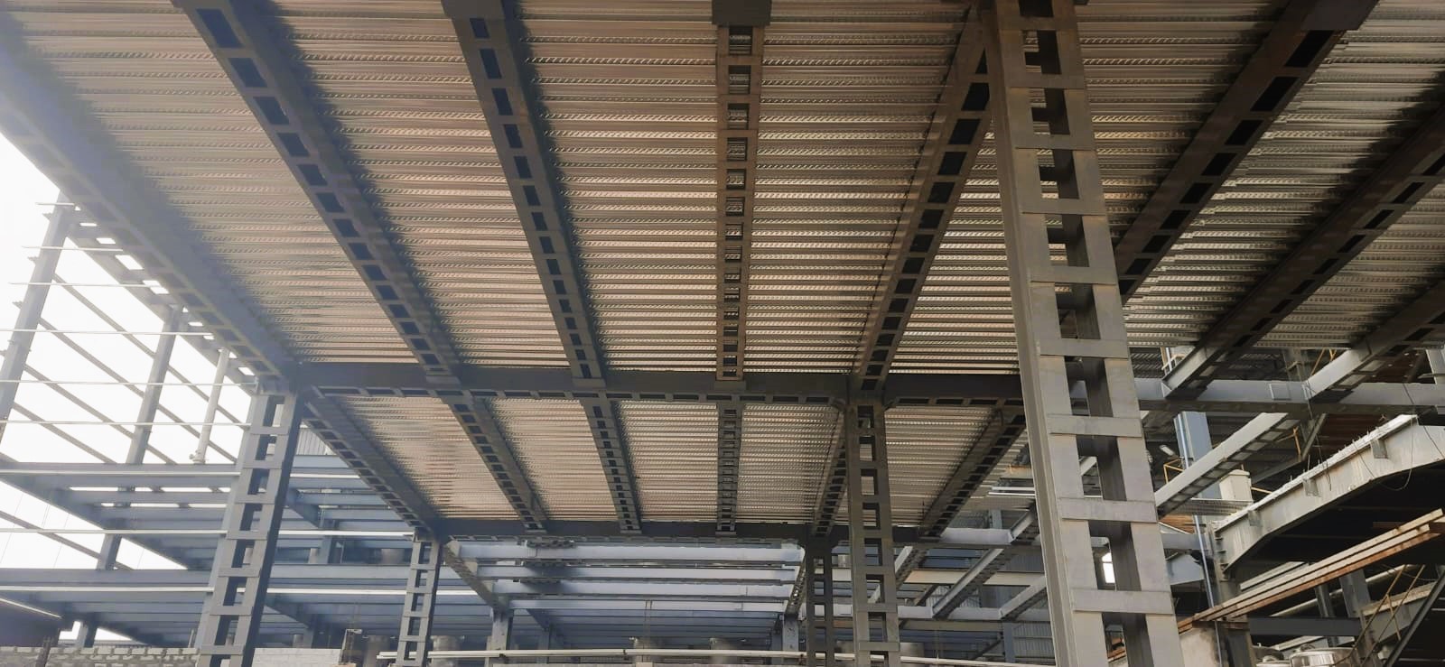 Under-view of a heavy-duty multi-story steel frame building showing composite metal floor decking and columns