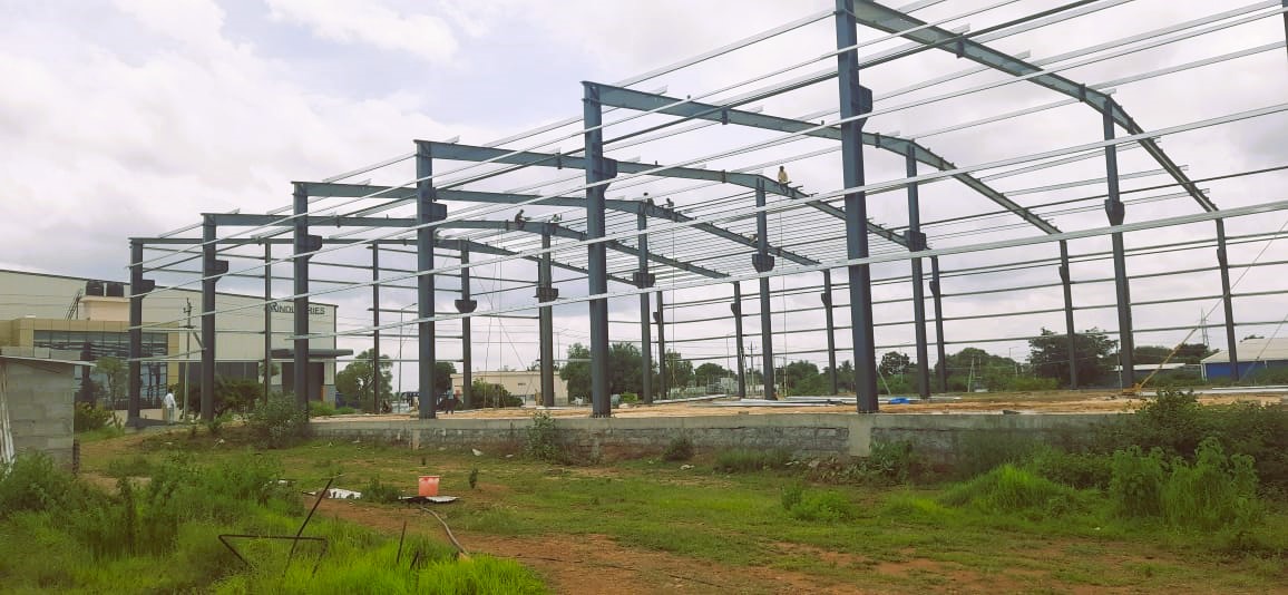 Wide landscape shot of heavy-duty pre-engineered building steel frame framework under cloudy sky