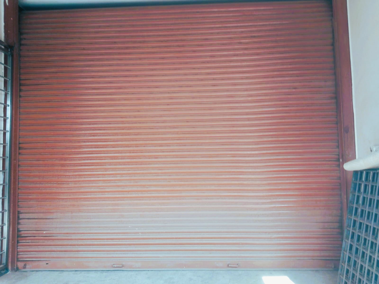 Heavy-duty red industrial rolling shutter door installed at warehouse entrance